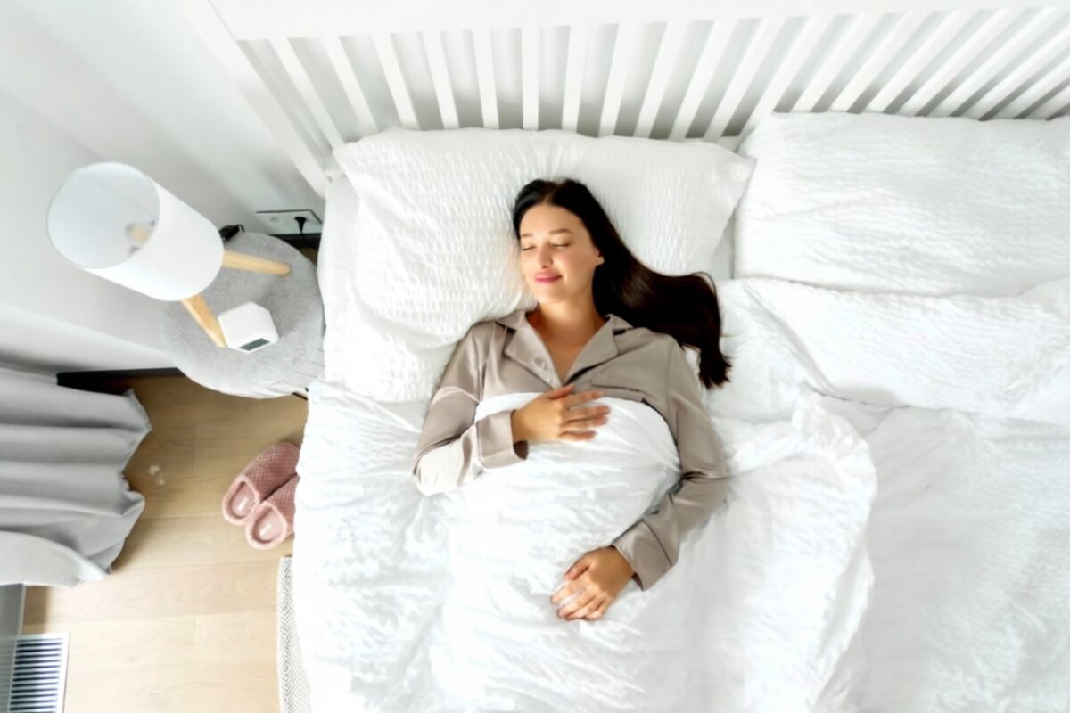 A woman sleeping on a bed in pajamas.