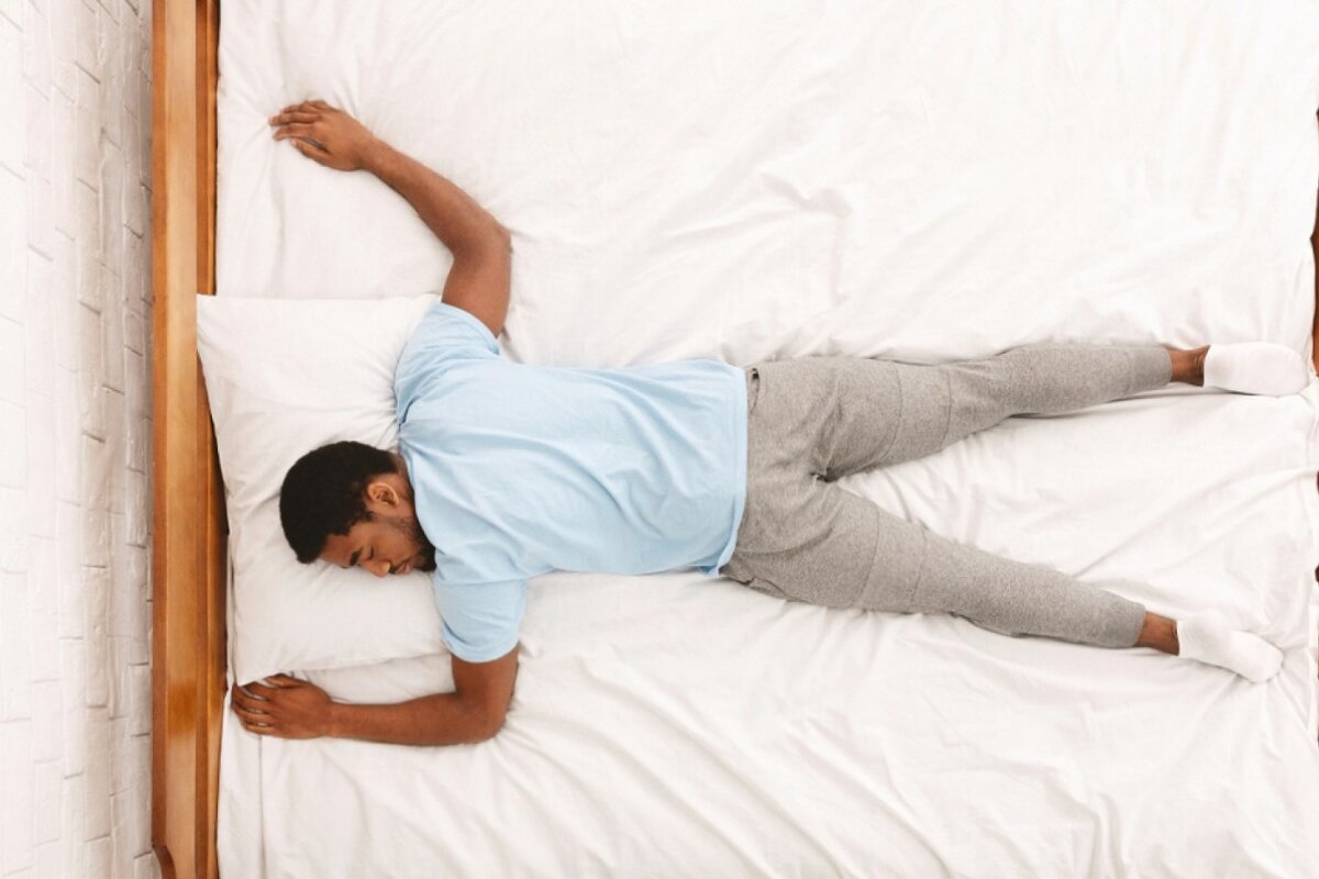 A man lying down on his stomach on a bed.