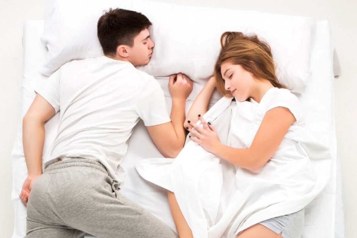 A couple sleeping on a bed.