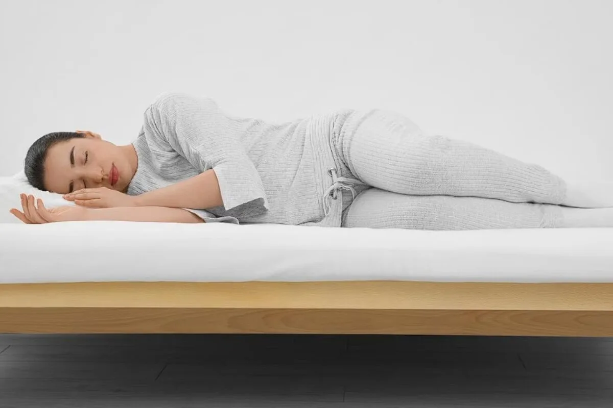 How Should Side Sleepers Sleep? A woman in white pajamas sleeping on a bed.