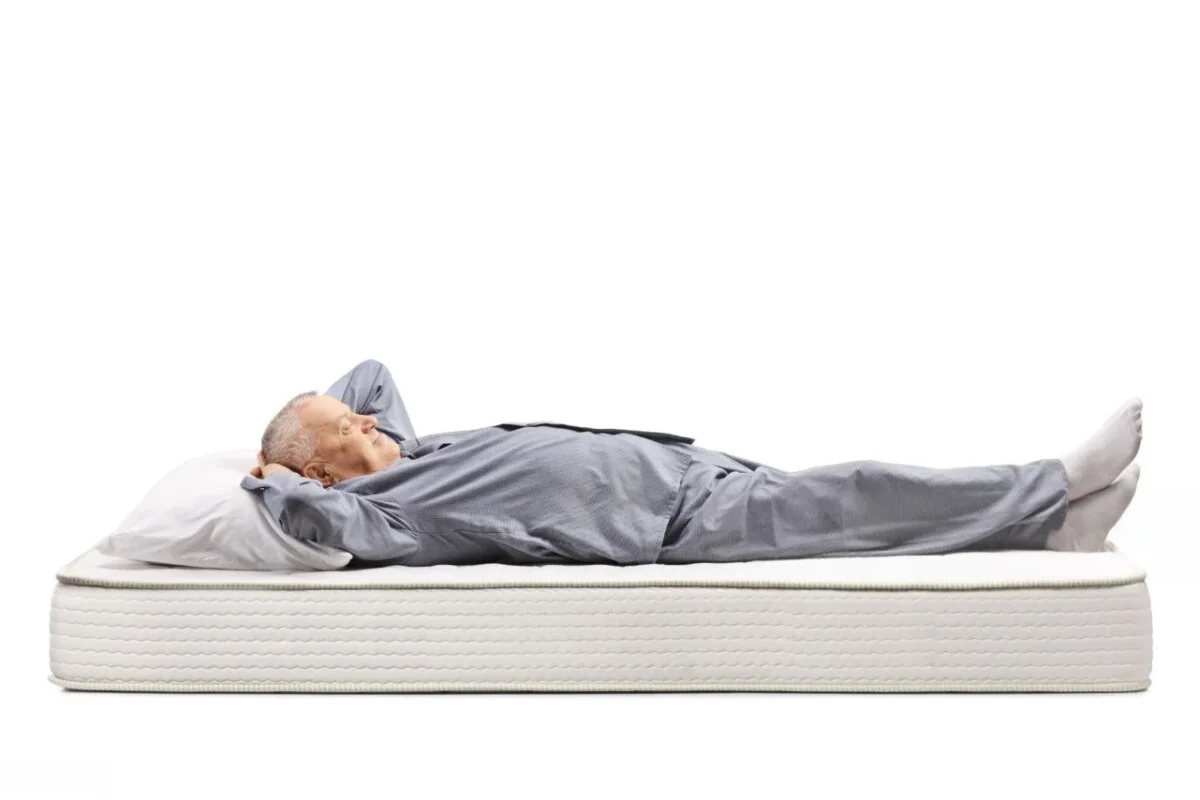 Is a Medium or Firm Mattress Better for Back Sleepers? An old man lying down on a mattress.