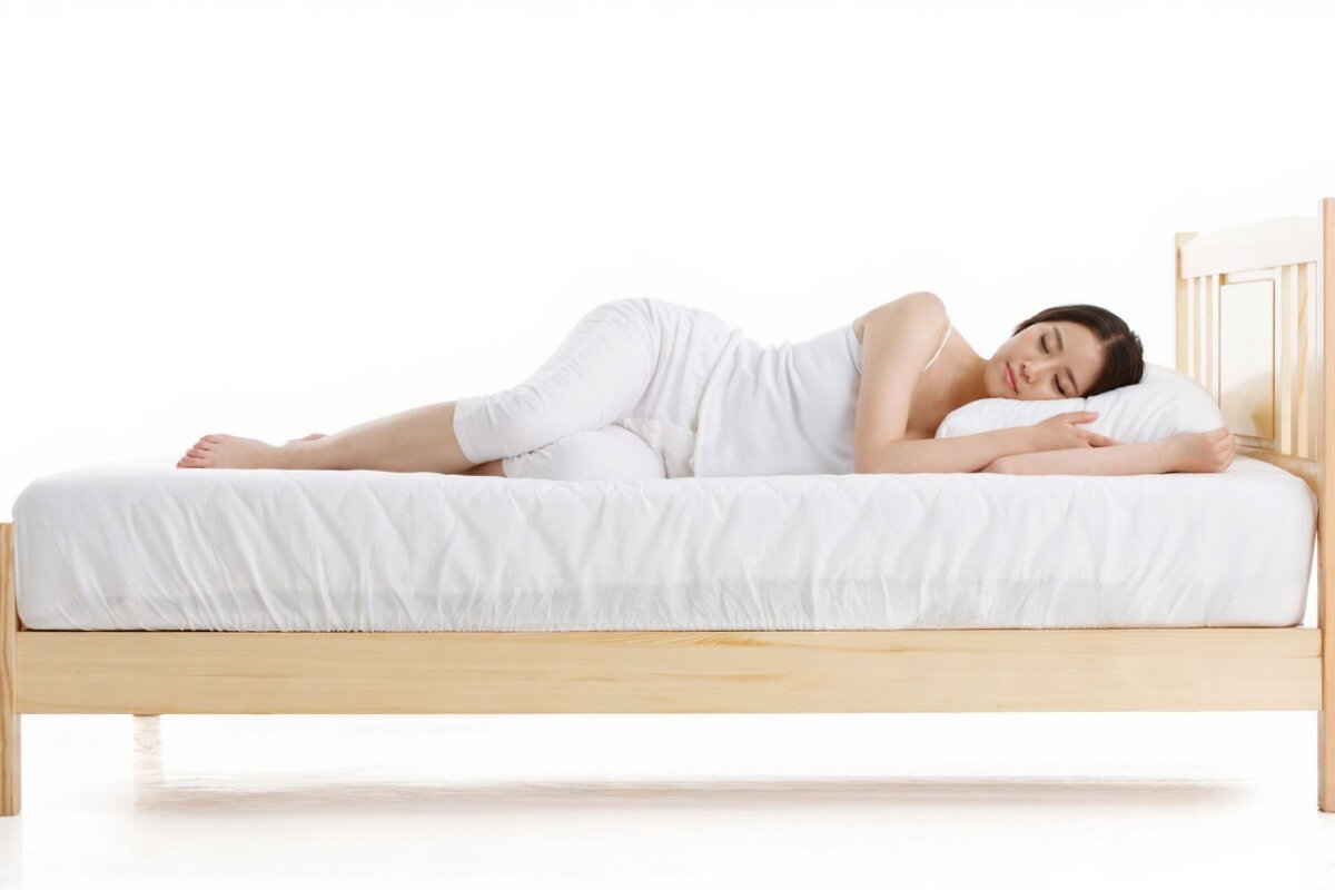 A woman sleeping on her side on a bed.