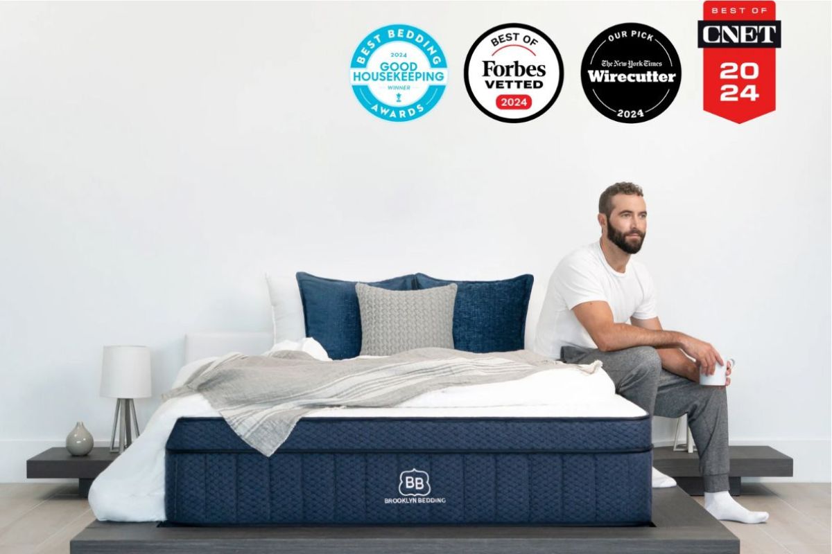 Brooklyn Bedding Aurora Luxe mattress with 2024 awards and reviewer sitting beside bed