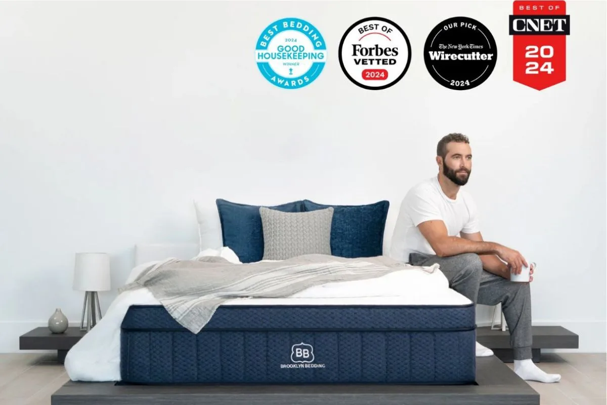 Brooklyn Bedding Aurora Luxe mattress with 2024 awards and reviewer sitting beside bed