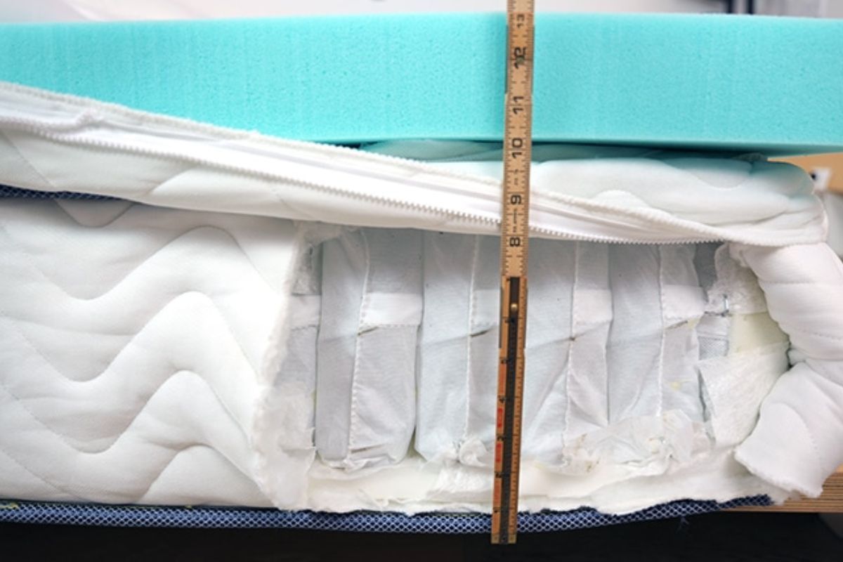 Mattress cutaway showing internal coils and foam layers with measuring ruler