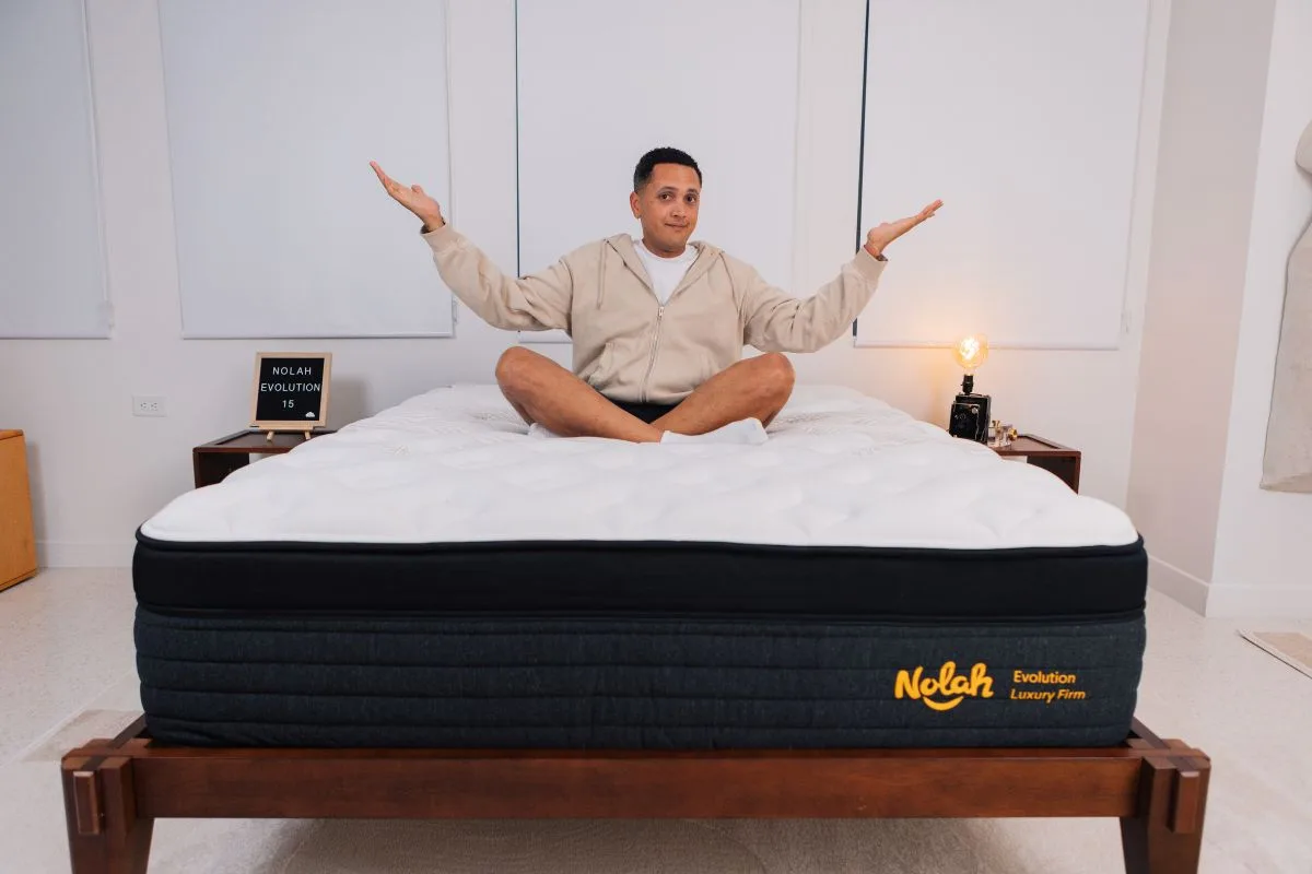 A man wearing comfortable clothes legs crossed with his arms in a shrug on a Nolah Evolution 15".