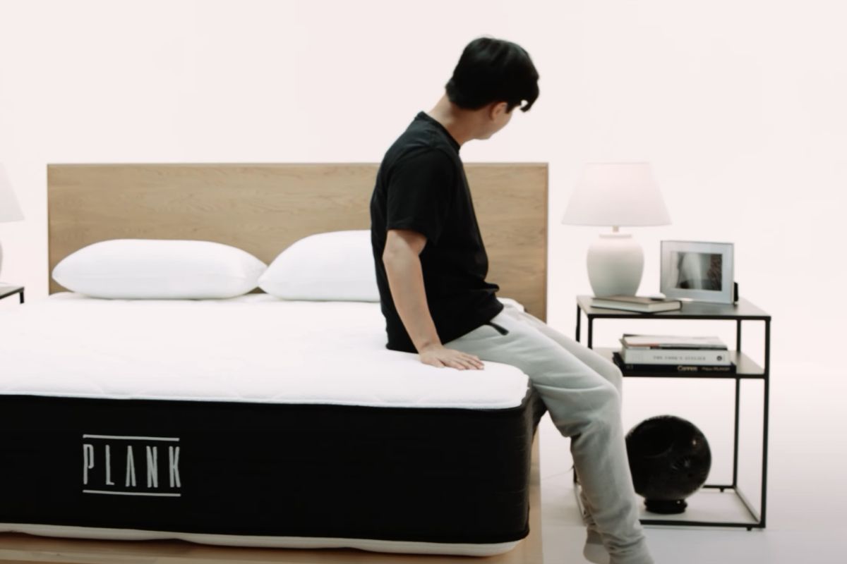 Person sitting on mattress edge demonstrating minimal sinkage and firm feel
