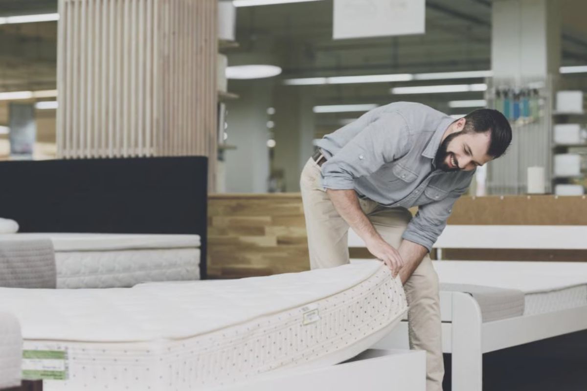 Man testing mattress in showroom to evaluate comfort before buying a California King mattress