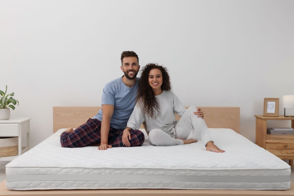 Couple sitting comfortably on a mattress, illustrating the importance of shared comfort and support when choosing the best mattress for couples