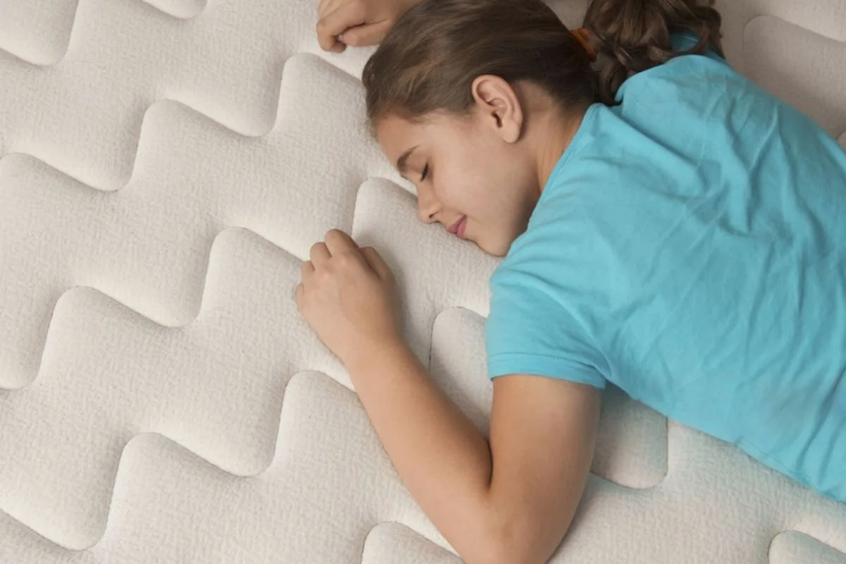 Child sleeping comfortably on a mattress, illustrating the importance of choosing the right mattress firmness for growing kids