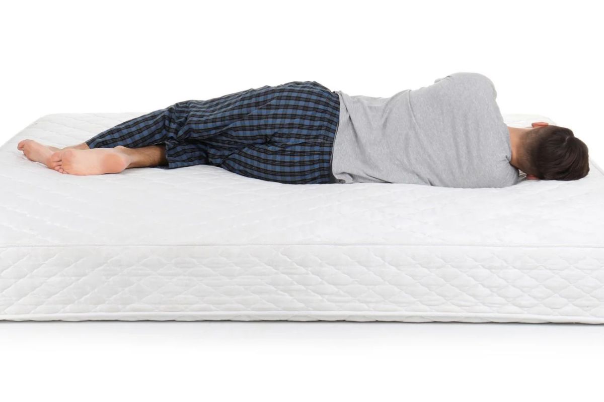 Side sleeper lying on an extra firm mattress, illustrating spinal alignment and pressure relief considerations for back pain sufferers