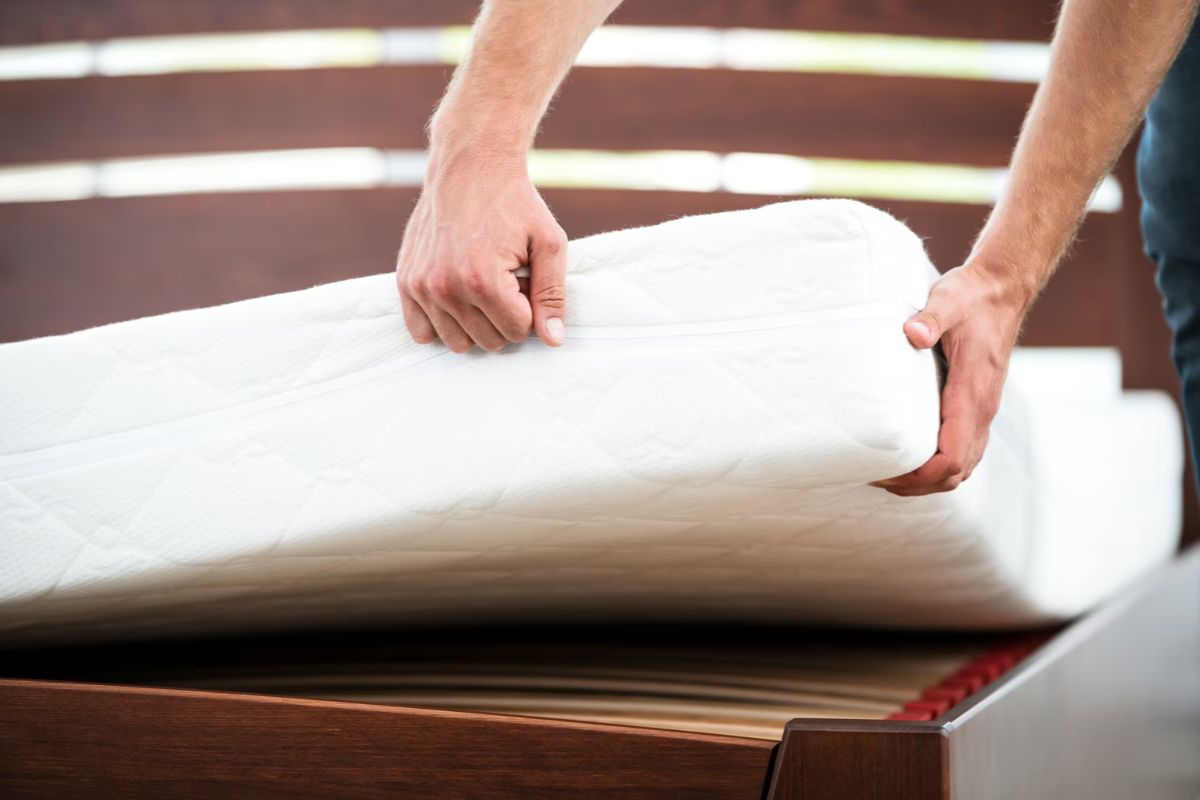 Hand pressing into a medium firm mattress to demonstrate the balanced level of cushioning and support typical of this firmness category.
