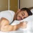 Man sleeping on his stomach with a supportive pillow to demonstrate proper stomach sleeping posture