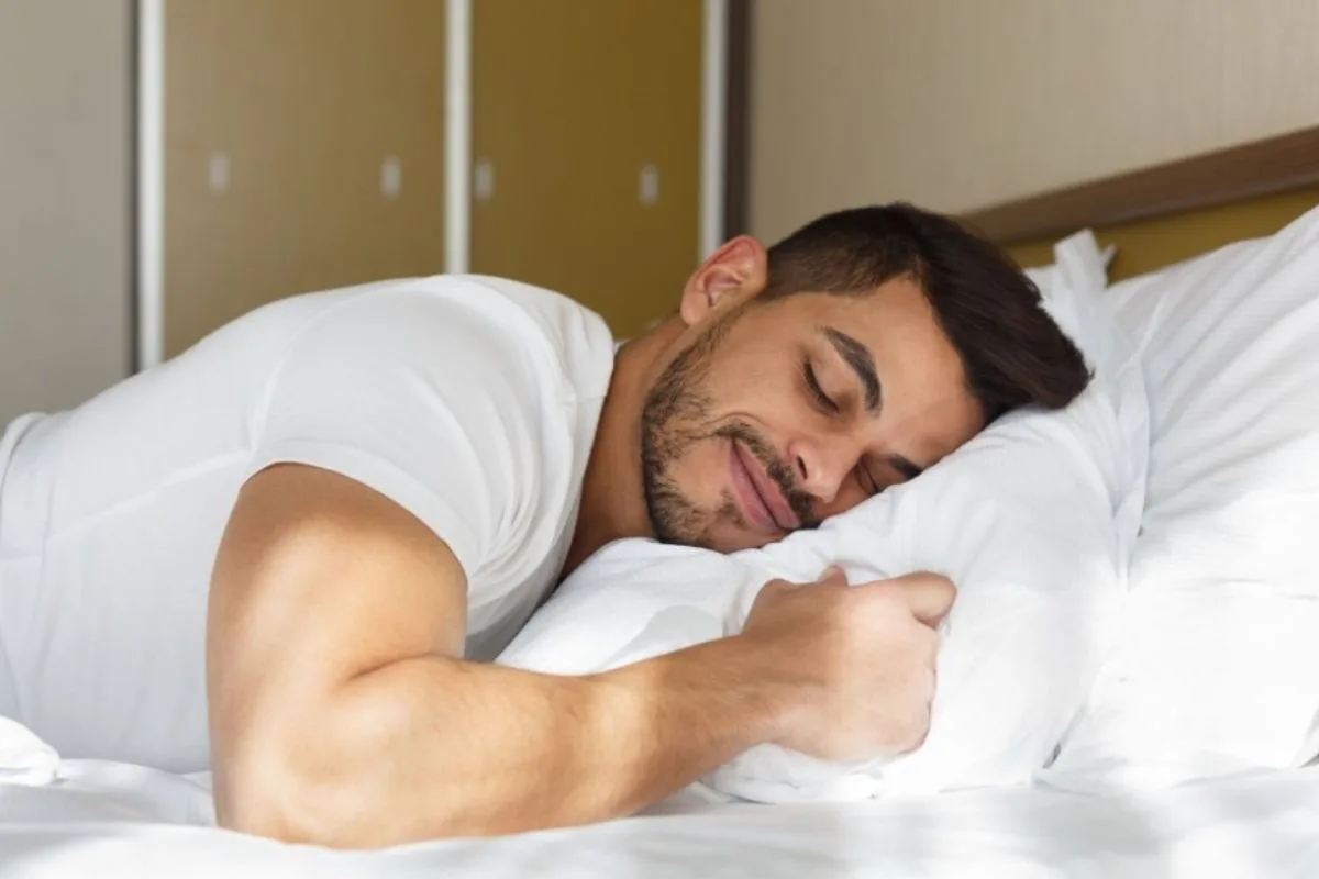 Man sleeping on his stomach with a supportive pillow to demonstrate proper stomach sleeping posture