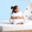 Young girl sitting comfortably on a mattress, illustrating the importance of choosing a supportive mattress for growing children