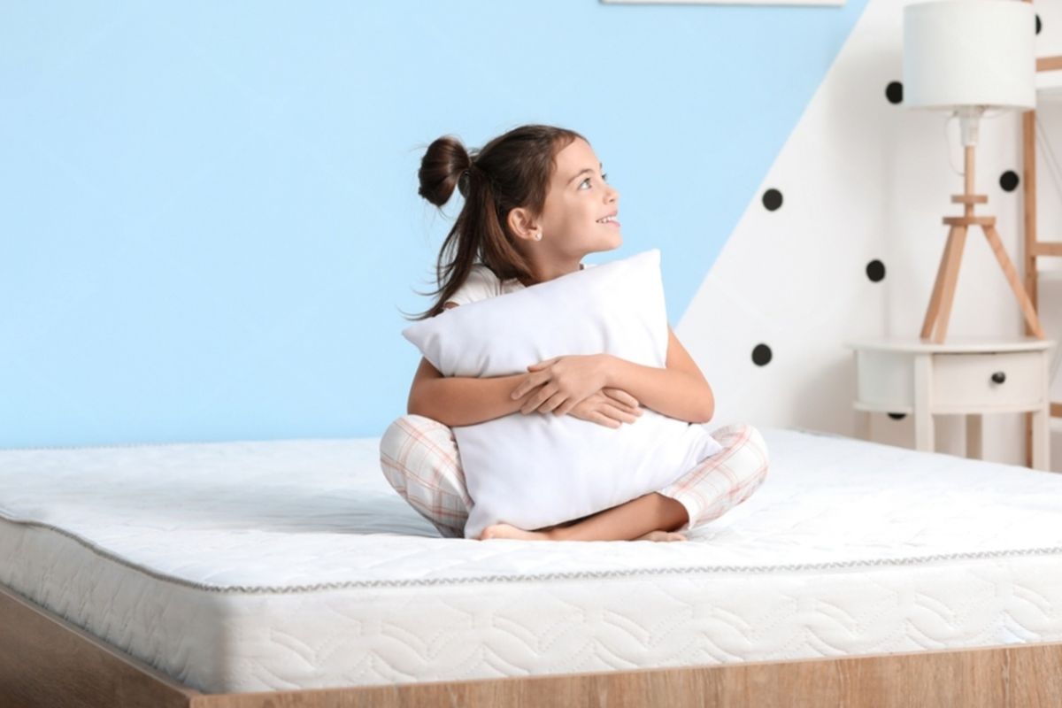 Young girl sitting comfortably on a mattress, illustrating the importance of choosing a supportive mattress for growing children