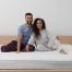 Couple sitting on a spring mattress, illustrating edge support, responsiveness, and shared comfort for couples
