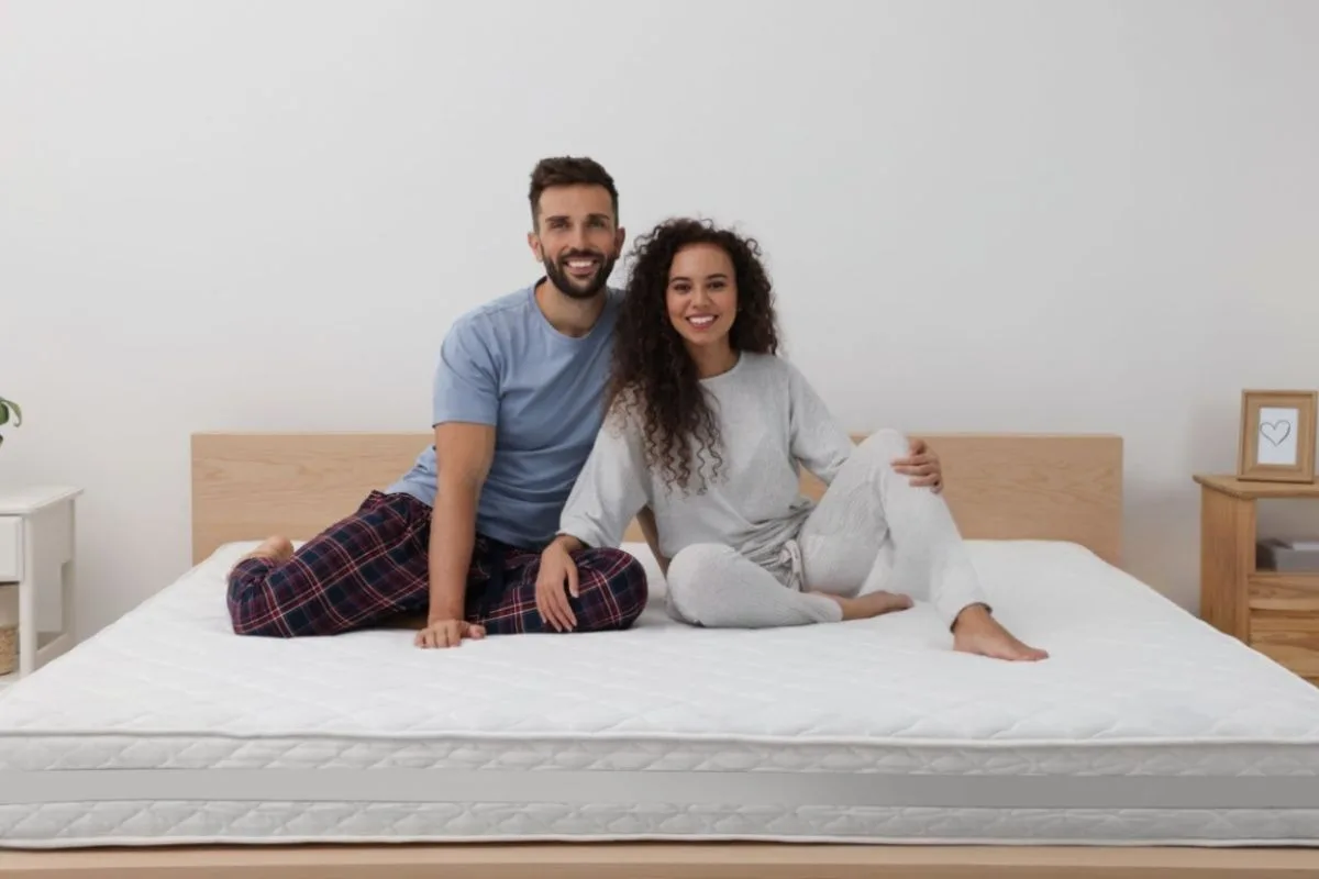 Couple sitting on a spring mattress, illustrating edge support, responsiveness, and shared comfort for couples