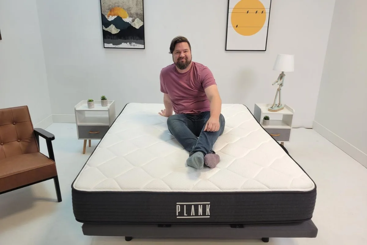 Reviewer sitting on a Plank Firm Luxe mattress during the sleep trial period, demonstrating the at-home testing experience for new owners