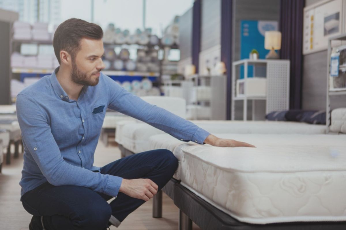 Shopper testing mattress firmness in a showroom, illustrating how combination sleepers can evaluate comfort and support before buying a mattress