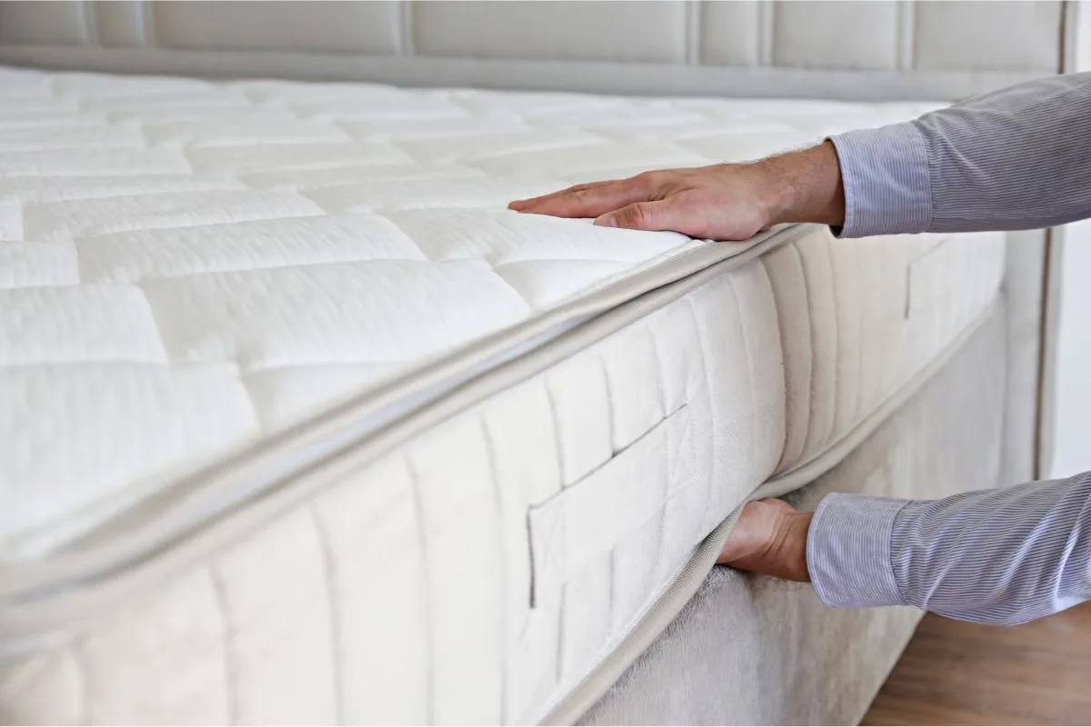 Hand pressing the surface of an extra firm mattress to demonstrate its minimal sinkage and supportive feel.