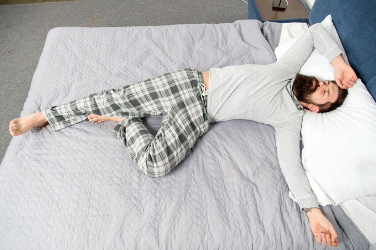 Back sleeper lying on a mattress in a relaxed position, demonstrating proper spinal support and body alignment for back sleepers