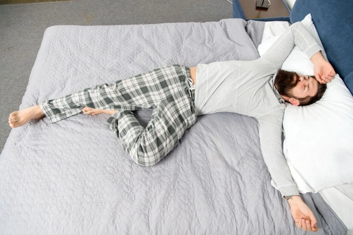 Back sleeper lying on a mattress in a relaxed position, demonstrating proper spinal support and body alignment for back sleepers
