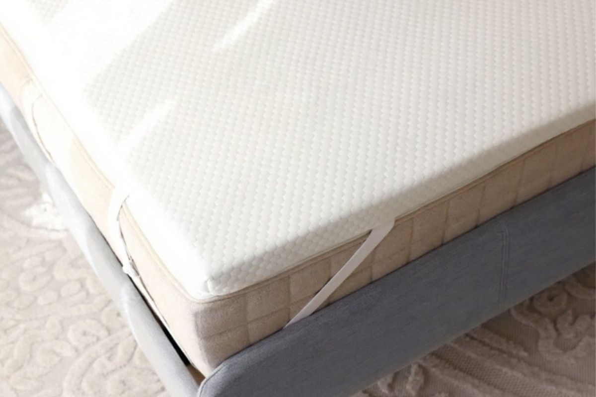 Close-up of a pressure-relieving mattress topper installed on a bed, illustrating how an added comfort layer can help reduce back discomfort during sleep