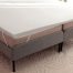Memory foam mattress topper secured with corner straps, showing a common solution used to add cushioning and improve back pain relief on an existing mattress