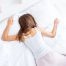 Stomach sleeper lying face down on a bed, illustrating the sleep position that often requires a softer, lower-loft pillow