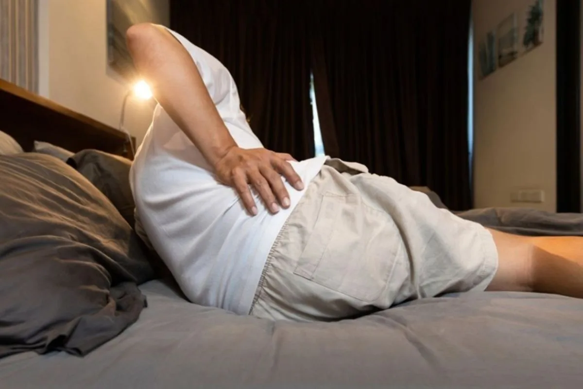 Do Stomach Sleepers Need a Soft or Firm Mattress? Person experiencing lower back discomfort from sleeping on a mattress that may be too soft for stomach sleepers
