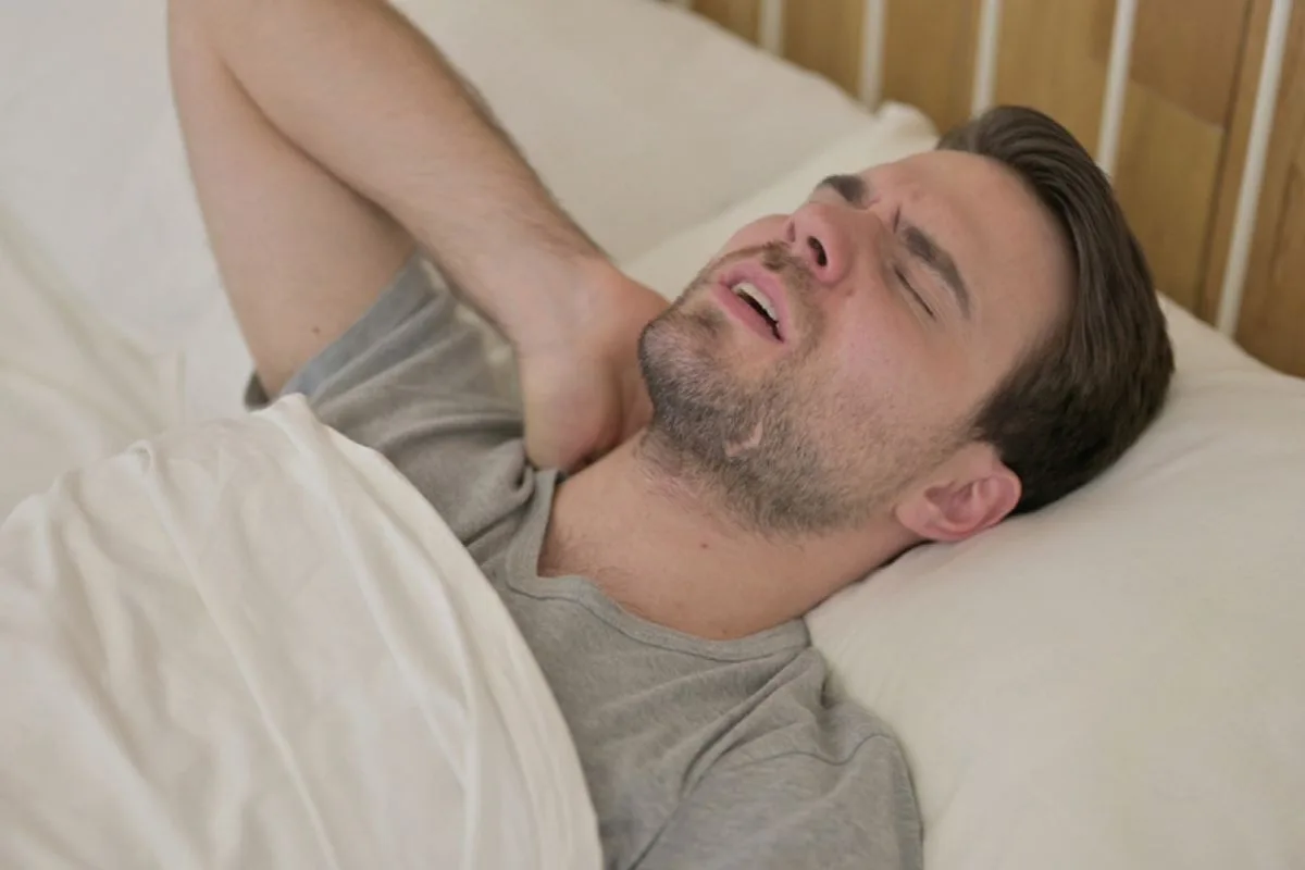 How High Should a Pillow Be for Back Sleepers? Back sleeper experiencing neck pain from incorrect pillow height, highlighting the importance of choosing the right loft