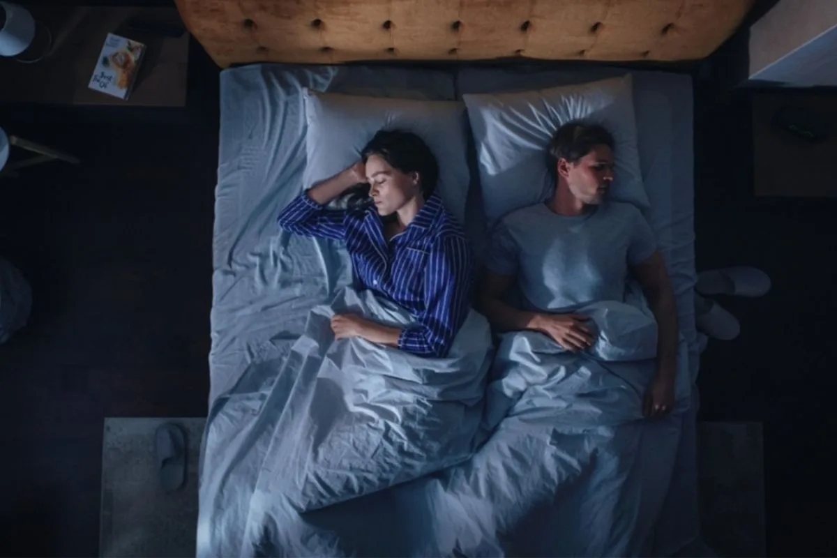 Couple sleeping in different positions to illustrate how the right mattress supports combination sleepers with minimal motion transfer