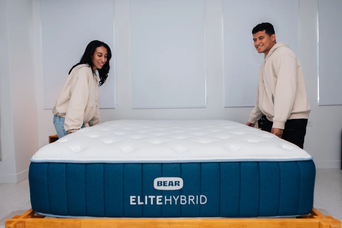 Mattress Advisory testers positioning a Bear Elite Hybrid mattress in our testing studio.