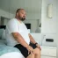 Heavy person sitting on the edge of a mattress, highlighting the importance of strong edge support and stability for easier sitting and getting in and out of bed