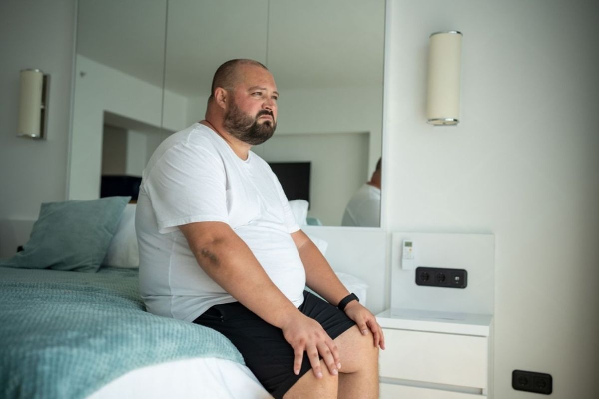 Heavy person sitting on the edge of a mattress, highlighting the importance of strong edge support and stability for easier sitting and getting in and out of bed